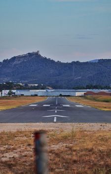 A runway surrounded by mountains and dry grass, ideal for aviation and travel themes.