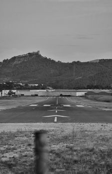 Runway leading to mountains, captured in black and white, offering a dramatic landscape view.