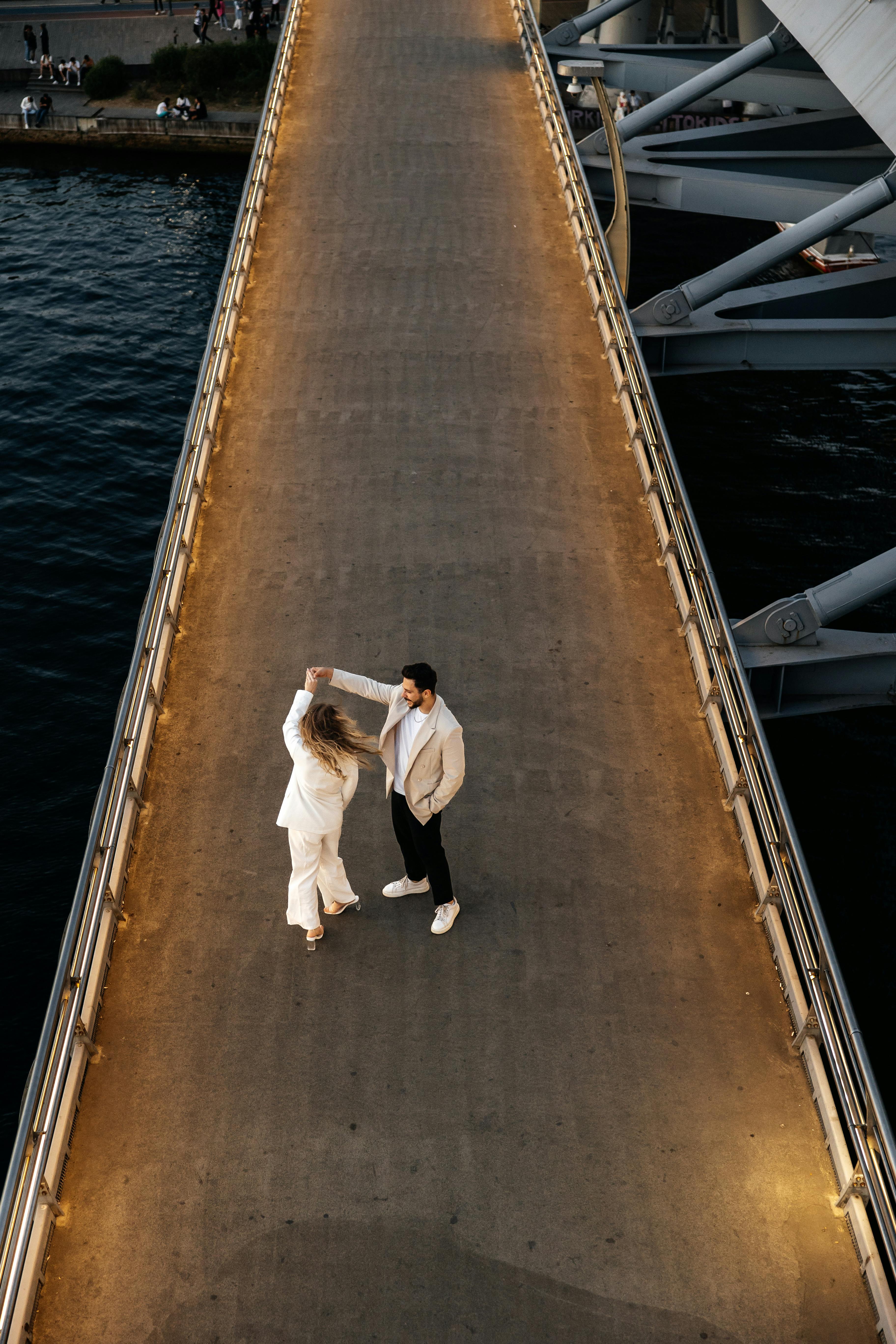 a couple is standing on a bridge over water