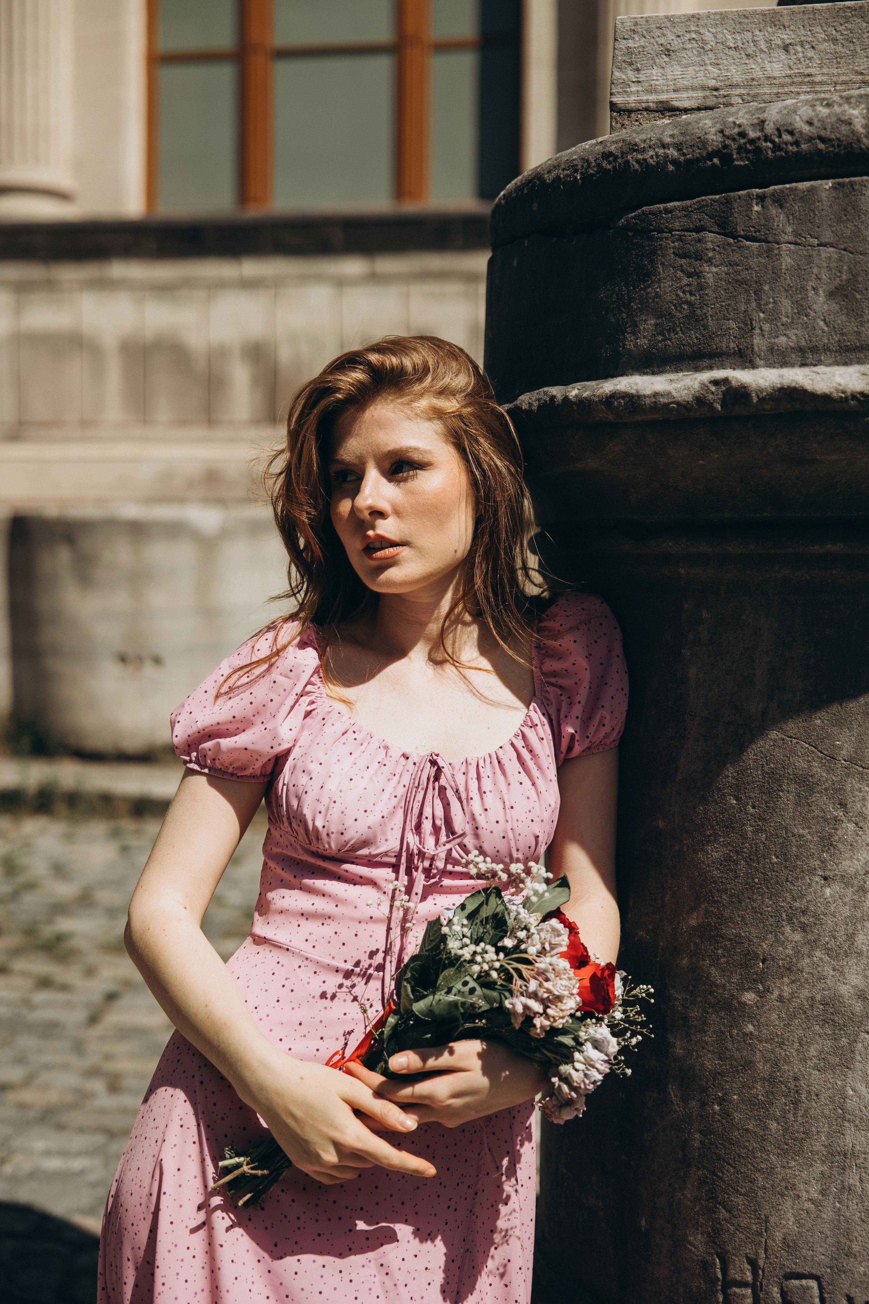 a woman in a pink dress holding flowers