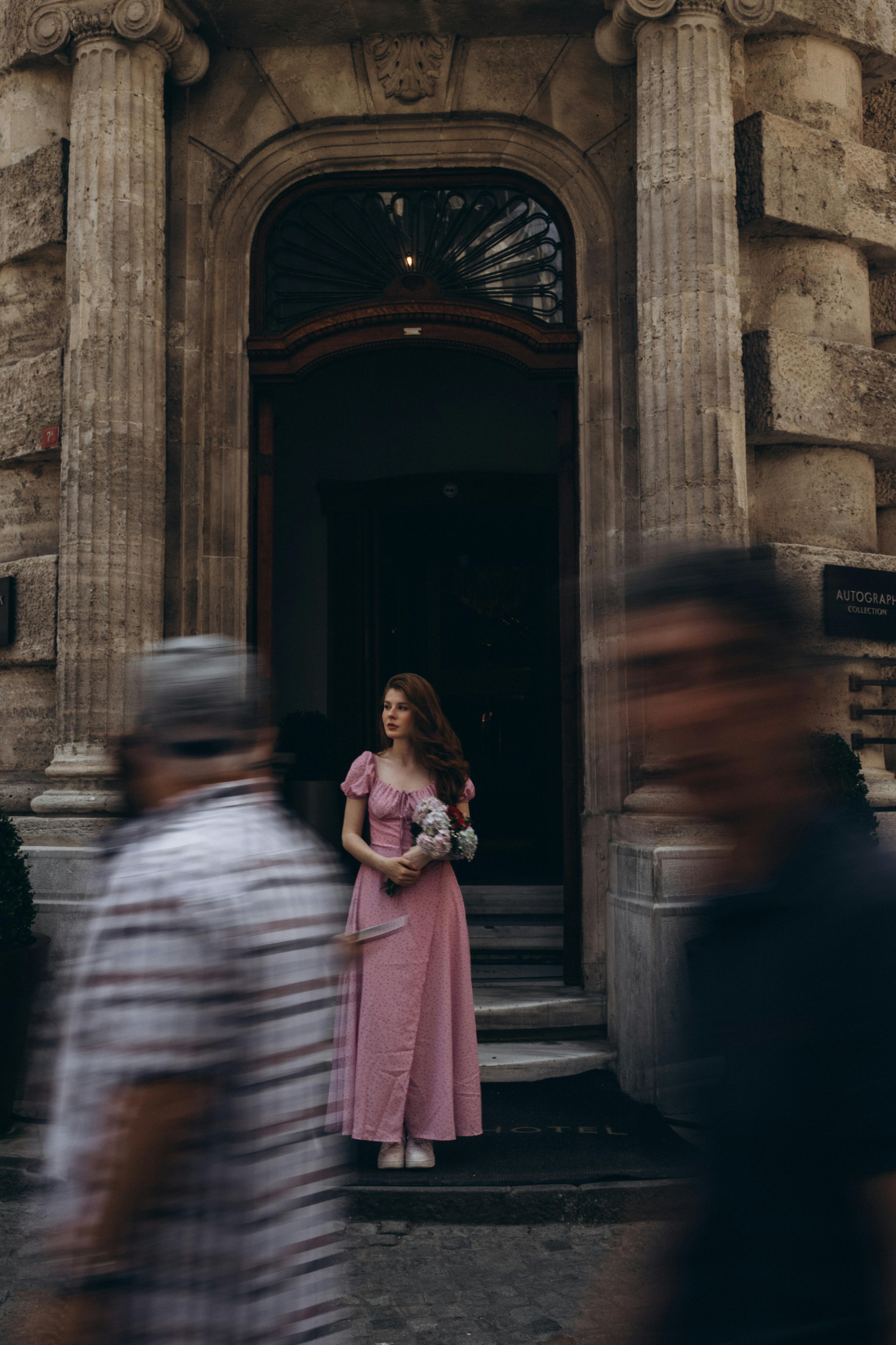 a woman in a pink dress is walking down a street