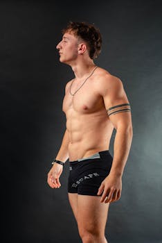 Portrait of a muscular man standing in underwear against a black background.