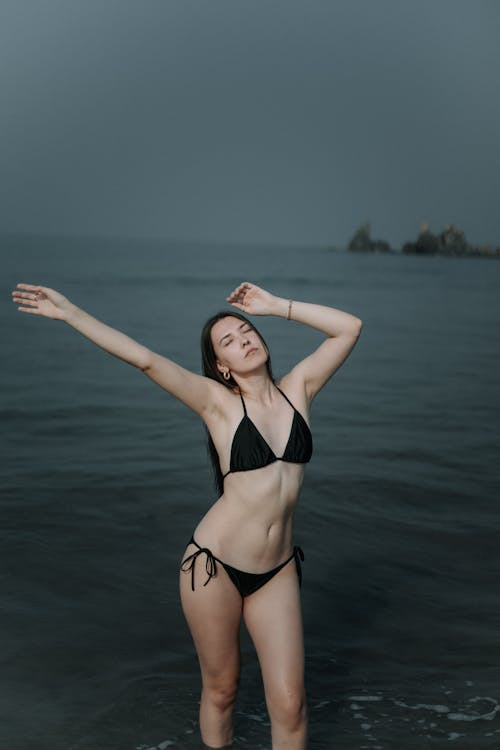 Woman in Bikini Standing with Arms Raised