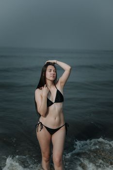 Woman in bikini posing peacefully by the sea, embracing summer vibes and tranquility.
