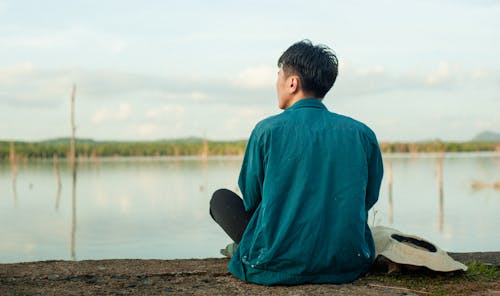 Man Sitting on Beach and Looking on Water