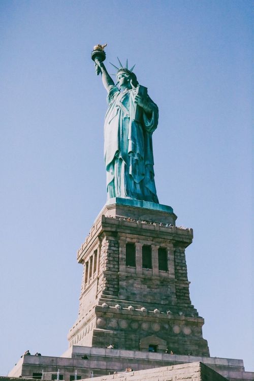 Free The Statue of Liberty stands tall in New York City's clear sky, a symbol of freedom. Stock Photo