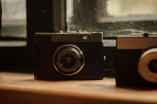 Free A classic vintage camera displayed on a wooden shelf, capturing nostalgic vibes. Stock Photo