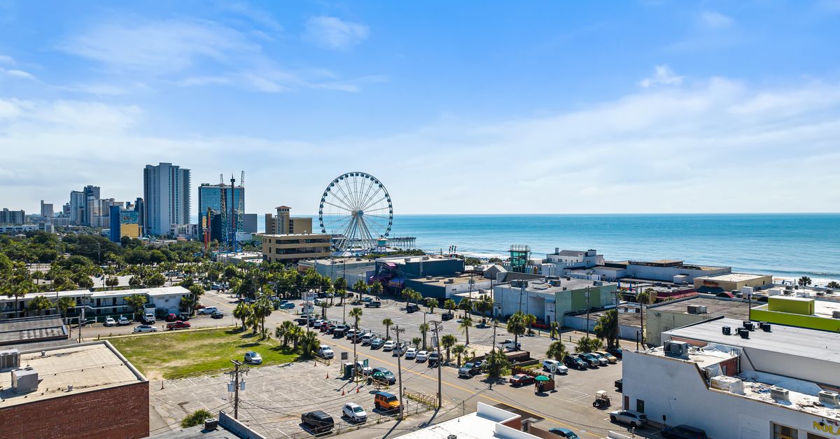 A vibrant aerial view of Myrtle Beach cityscape with Ferris wheel and ocean in the background.