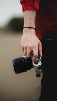A close-up shot of a photographer's hand holding a camera outdoors, emphasizing creativity and artistry.