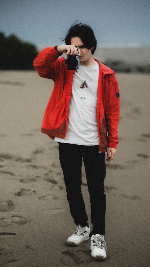 Young Man in Red Jacket with Camera in Hand