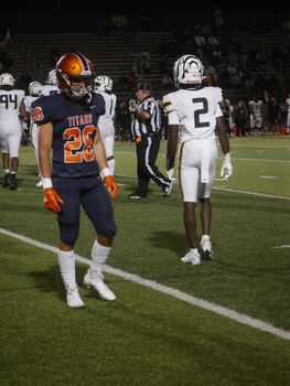 Intense high school football game at night, players in action on the field.