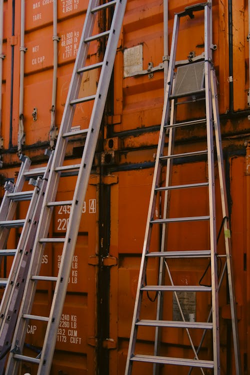 Metal Ladders Leaning on Red Containers