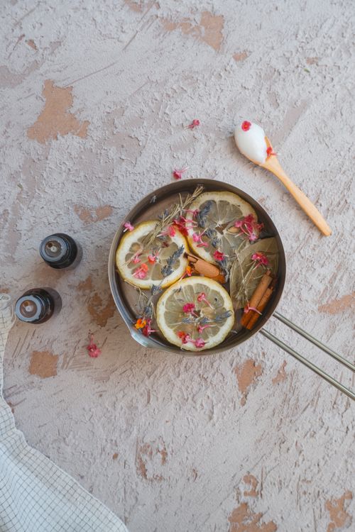 Free Top view of an aromatic potpourri arrangement with lemon slices and herbs in a pot on a textured surface. Stock Photo