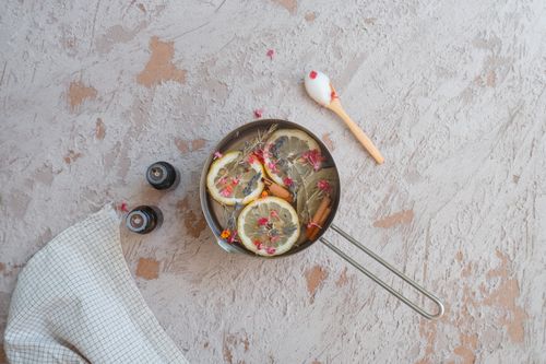 Free Aromatherapy setting with lemon slices and essential oils in a pot on textured surface. Stock Photo
