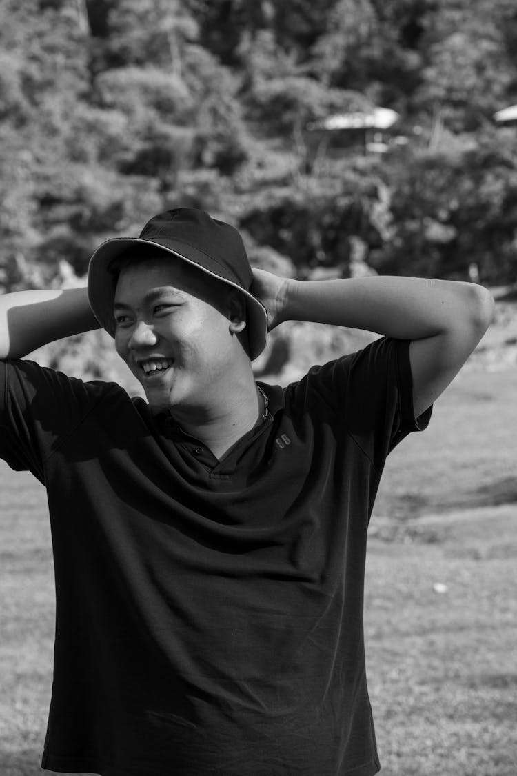 Young Man In A Bucket Hat Standing Outside In Summer And Smiling 