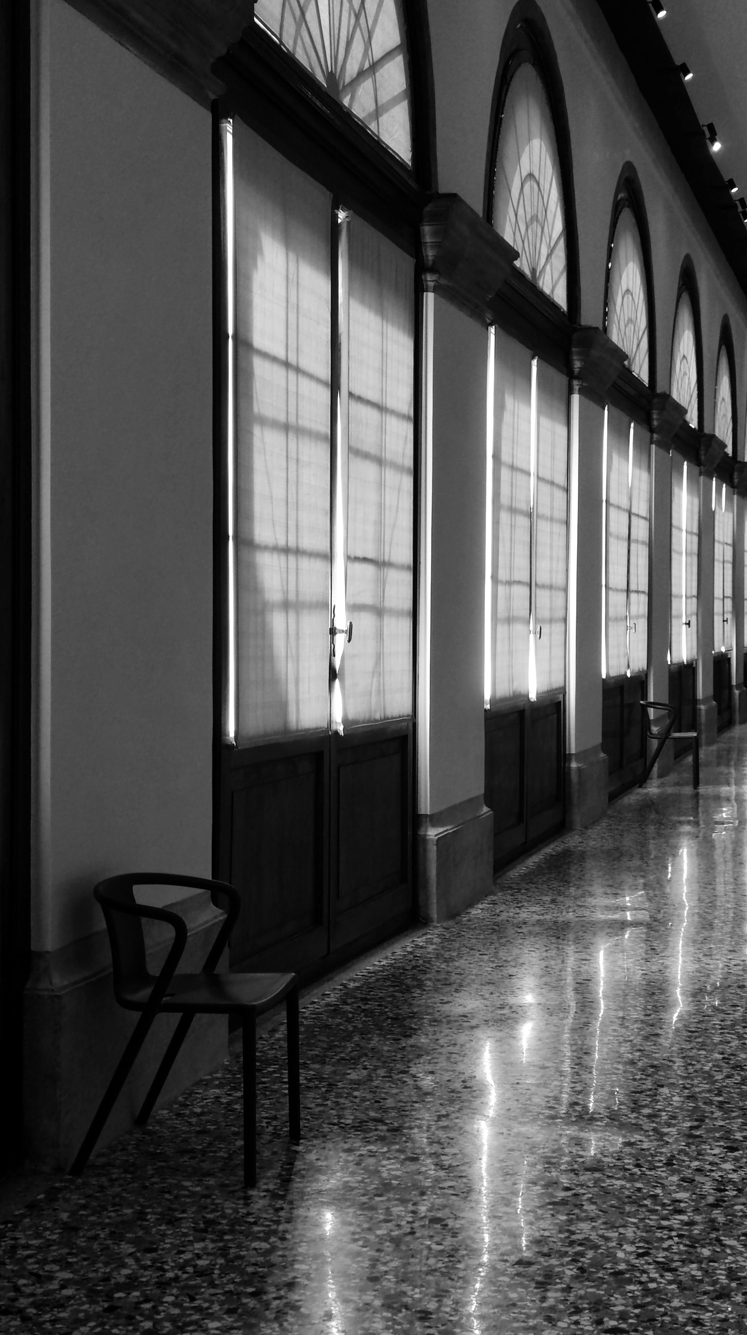 Black and white shot of Venetian interior featuring arched windows and reflective floors.