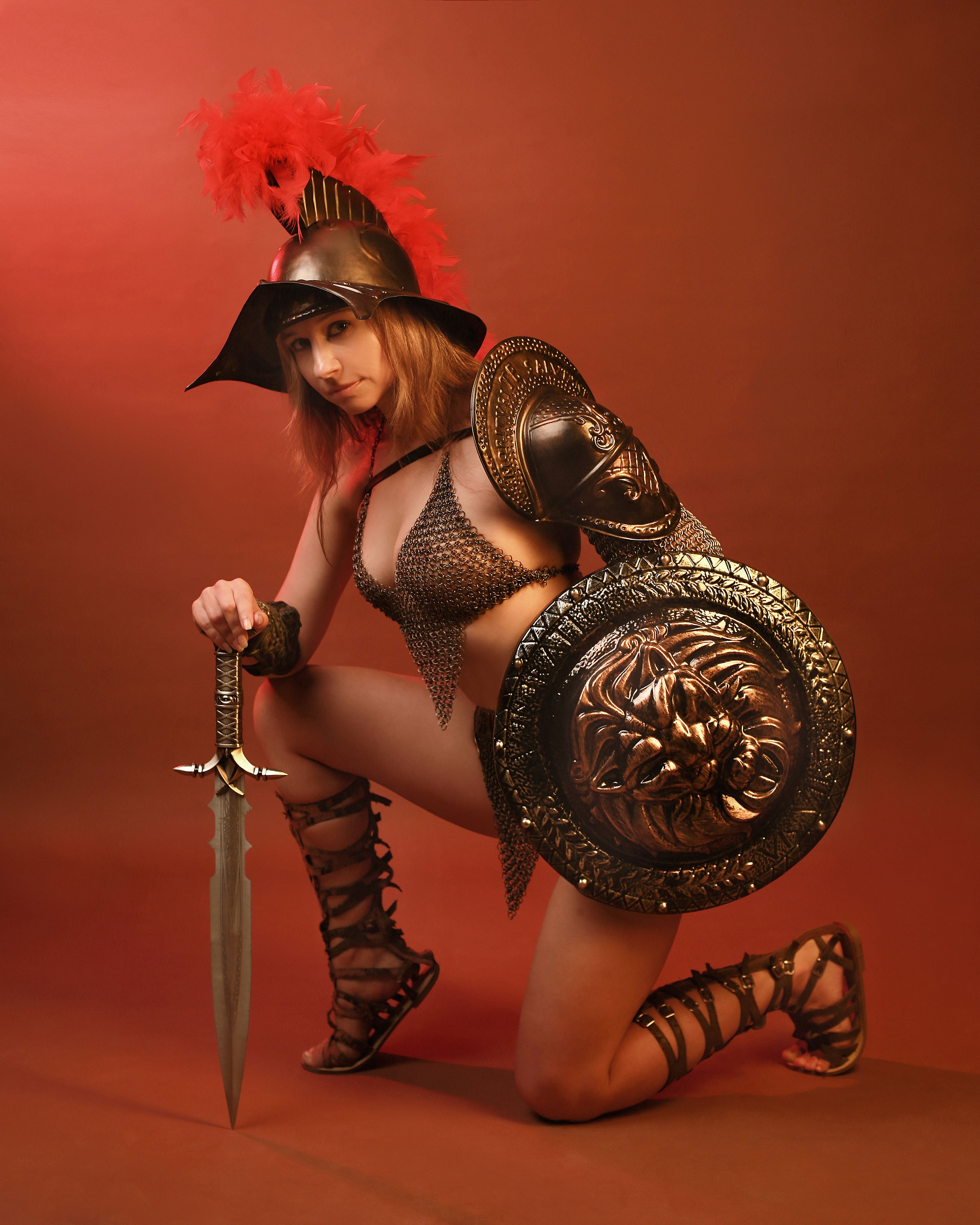 A female warrior posing in a dramatic costume with a lion shield and sword.