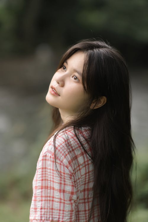 Young Woman in a Checkered Shirt Standing Outside 