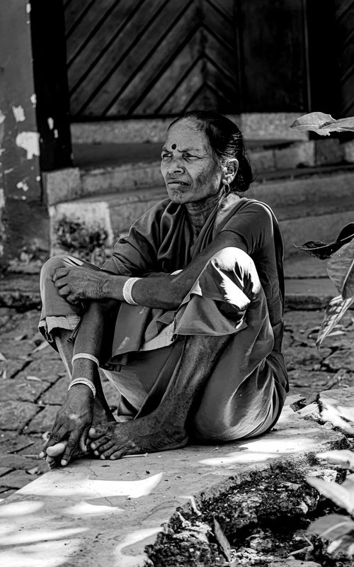 Free Elderly South Asian woman sitting on steps in traditional attire. Stock Photo