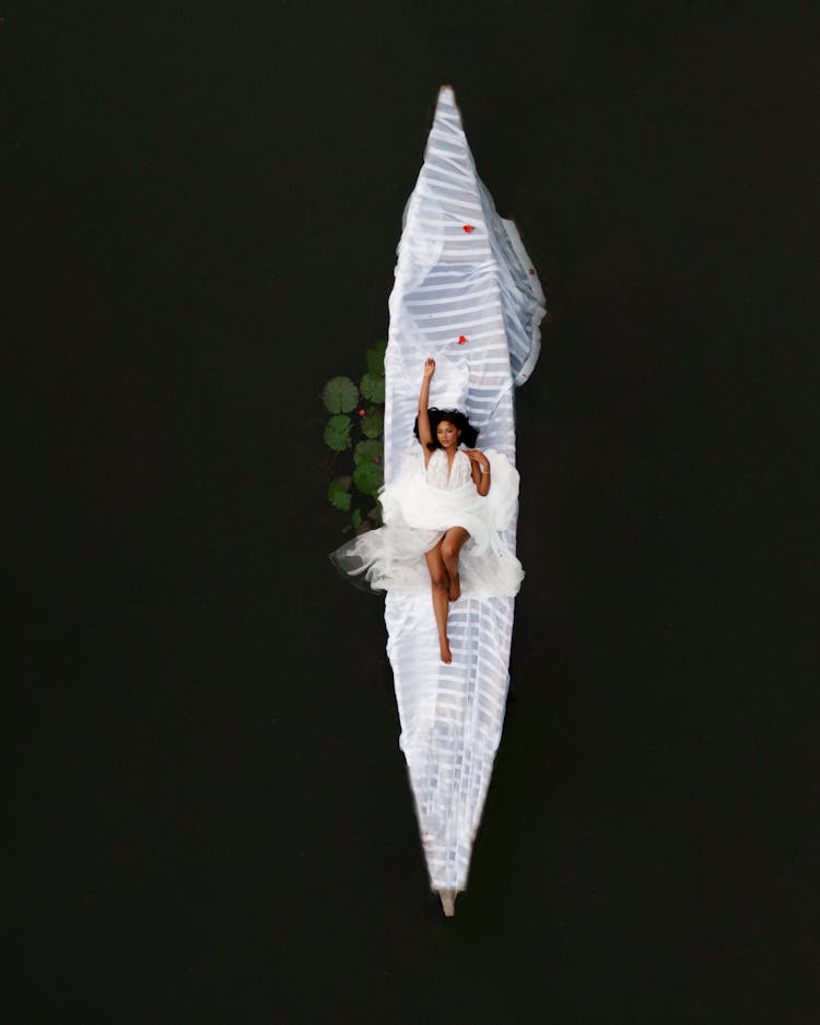 Young Black Bride Lying On Canoe Boat In Water