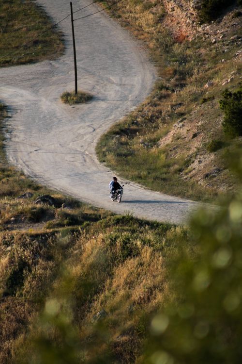 Free A person riding a motorbike on a winding road in the countryside, surrounded by nature. Stock Photo