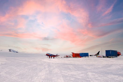 Stunning view of an Antarctic airstrip with colorful aircraft at sunset, showcasing adventure and exploration.
