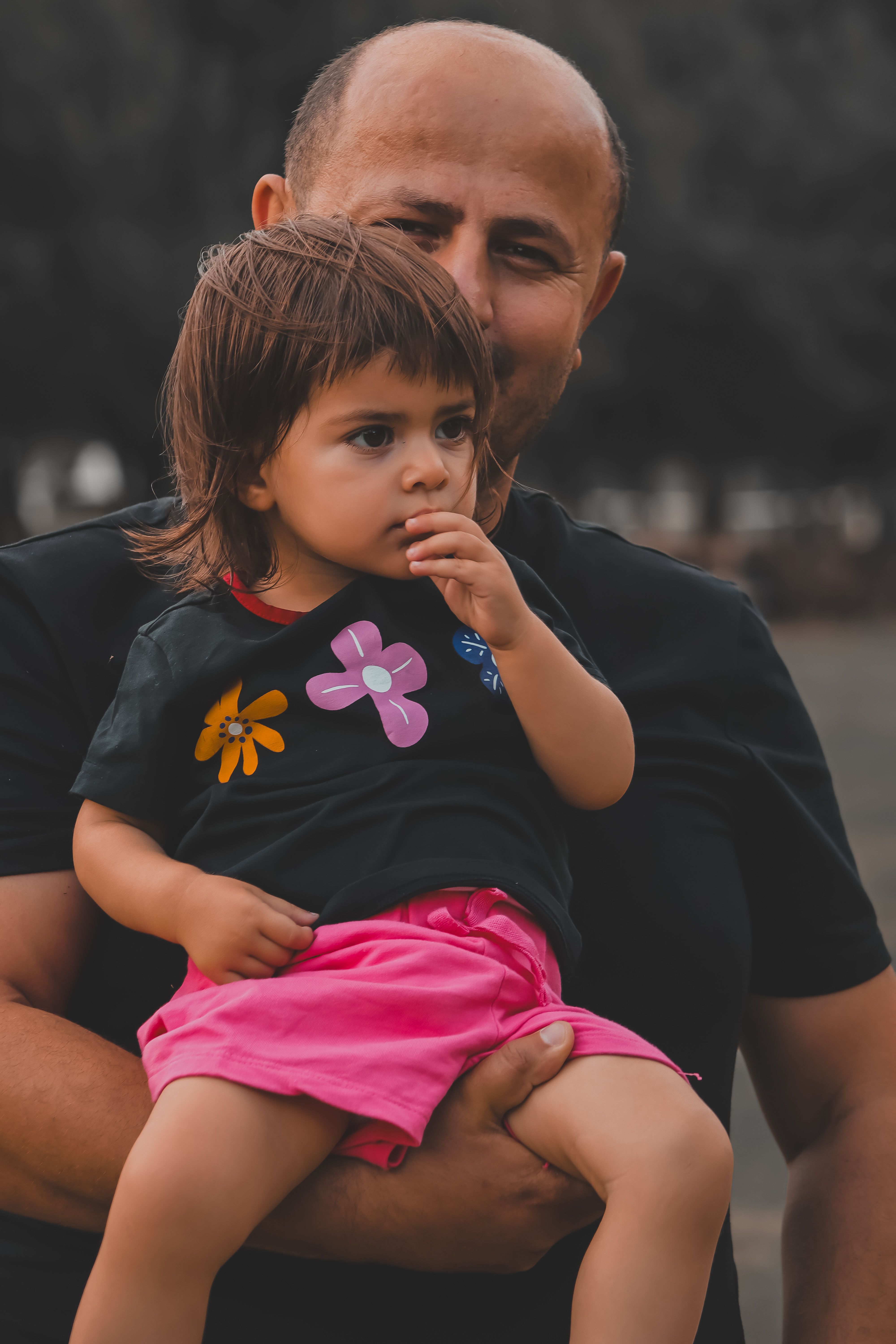 A father lovingly holding his daughter in a park, capturing family moments.