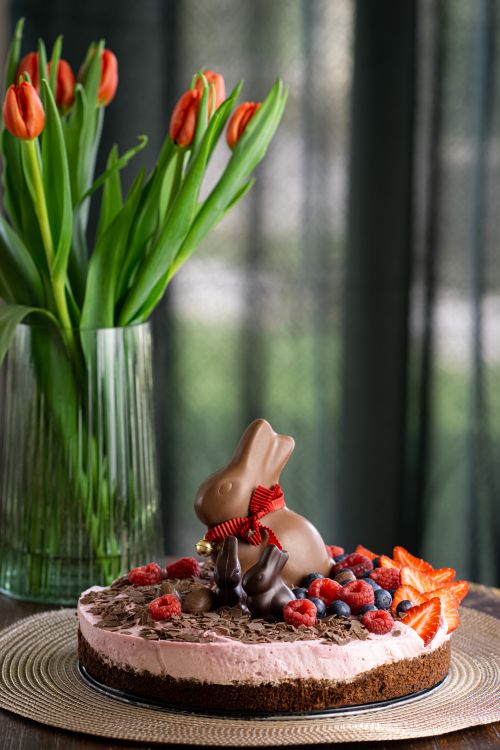 Free Delightful Easter cake topped with a chocolate bunny, berries, and floral decorations. Stock Photo
