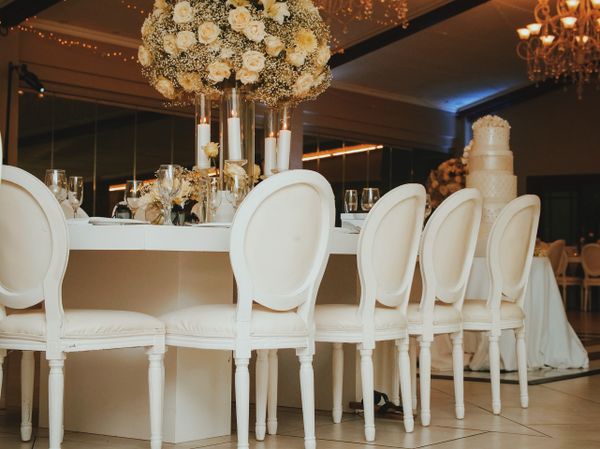 Head table with white chairs and tall florals