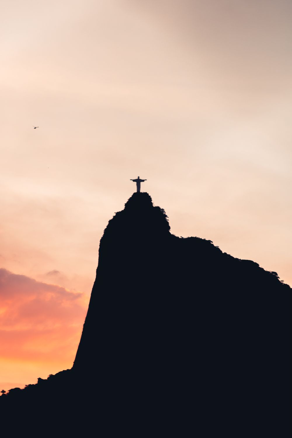 Silueta del Cristo Redentor al ocaso recortada contra el cielo rosado de Río de Janeiro
