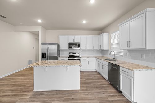 Free Spacious modern kitchen featuring white cabinetry, stainless steel appliances, and a center island. Stock Photo