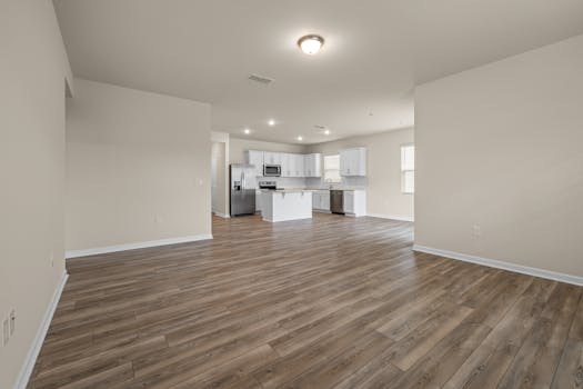 Open layout with wooden floors and modern kitchen in a bright empty room.