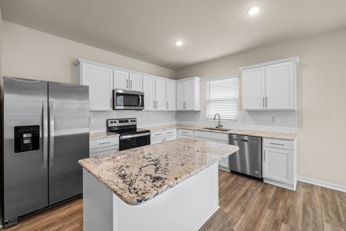 Free Spacious kitchen featuring a marble island, stainless steel appliances, and white cabinetry. Stock Photo