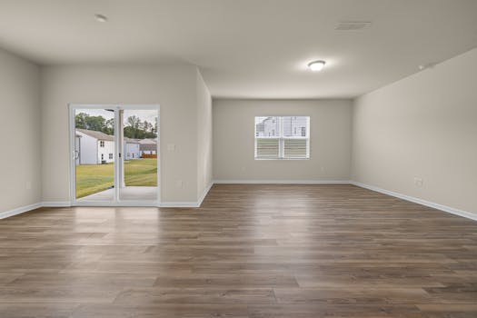 Bright and spacious minimalist living room interior with wooden flooring and garden view.