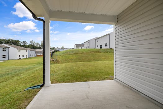 A quiet suburban patio with a view of multiple houses and a green lawn under a blue sky.