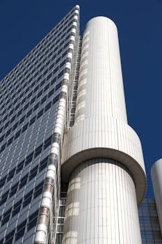 现代摩天大楼采用独特的圆柱形设计，在低角度视角下映衬着清澈的蓝天