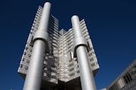 蔚蓝的天空下，矗立着一座拥有玻璃立面和钢柱的未来派办公摩天大楼