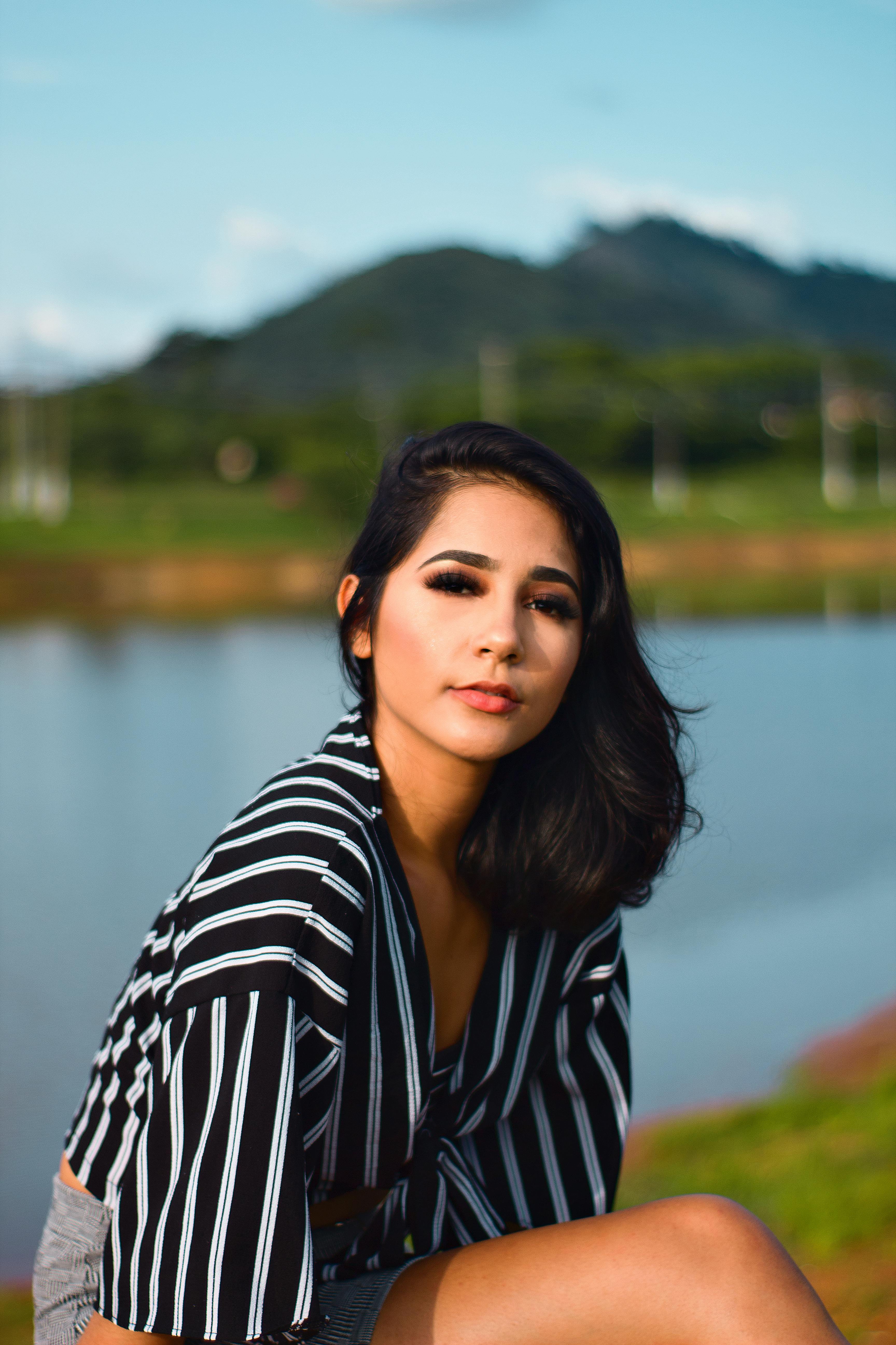 在风景优美的山峰背景下，时尚模特于宁静的湖边摆出优雅而时尚的姿势