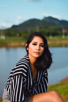 在风景优美的山峰背景下，时尚模特于宁静的湖边摆出优雅而时尚的姿势