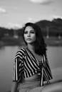 湖边宁静，一位身着条纹连衣裙的女子黑白肖像
