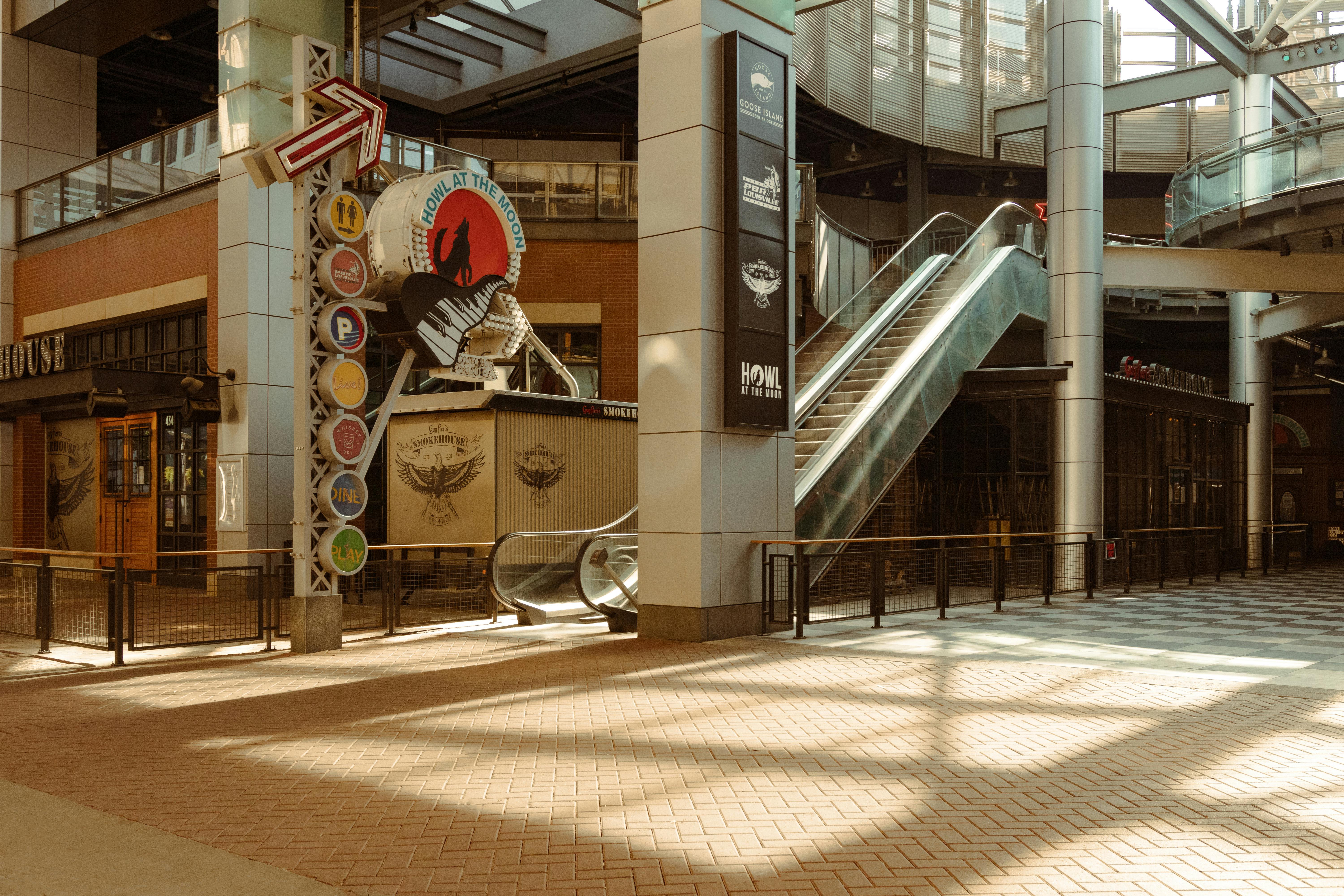 Spacious shopping mall interior featuring escalators and vibrant signage in Louisville, KY.