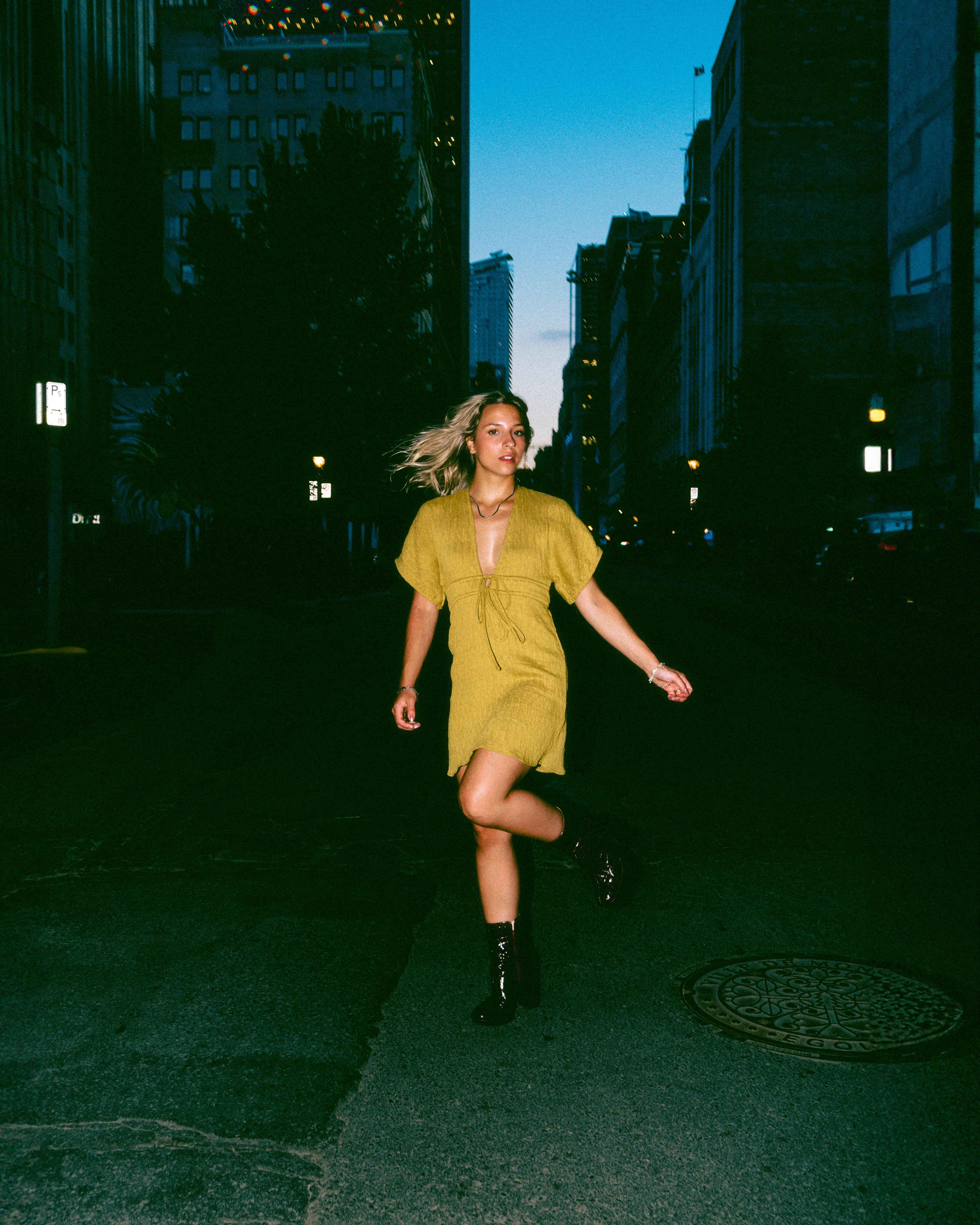 A woman in a green dress runs through the streets of Montréal during twilight.