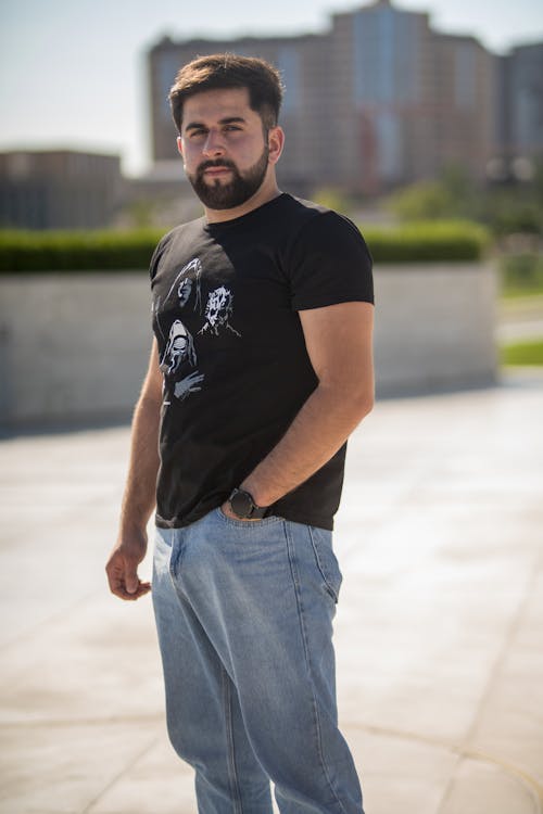 A Bearded Man in a Casual Outfit Standing on the Pavement 