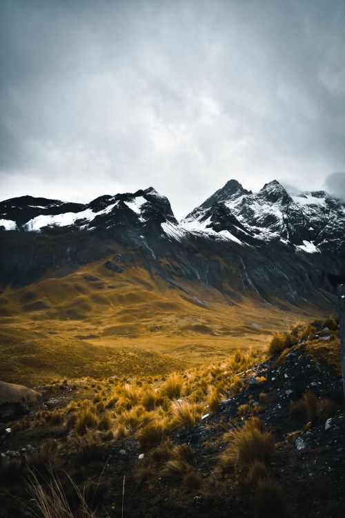 Free Capture of striking snow-capped mountain peaks beneath dark, moody rain clouds. Stock Photo