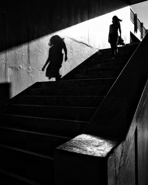 Black and white photo capturing a woman's silhouette on stairs in an urban setting, Istanbul.