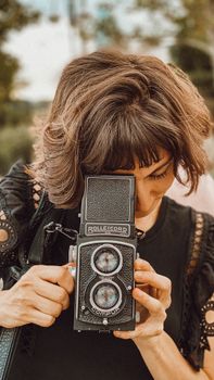 Woman in Baku using a vintage twin-lens camera, capturing portraits outdoors.