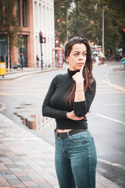 Free Woman in casual attire stands thoughtfully on a busy London street. Stock Photo