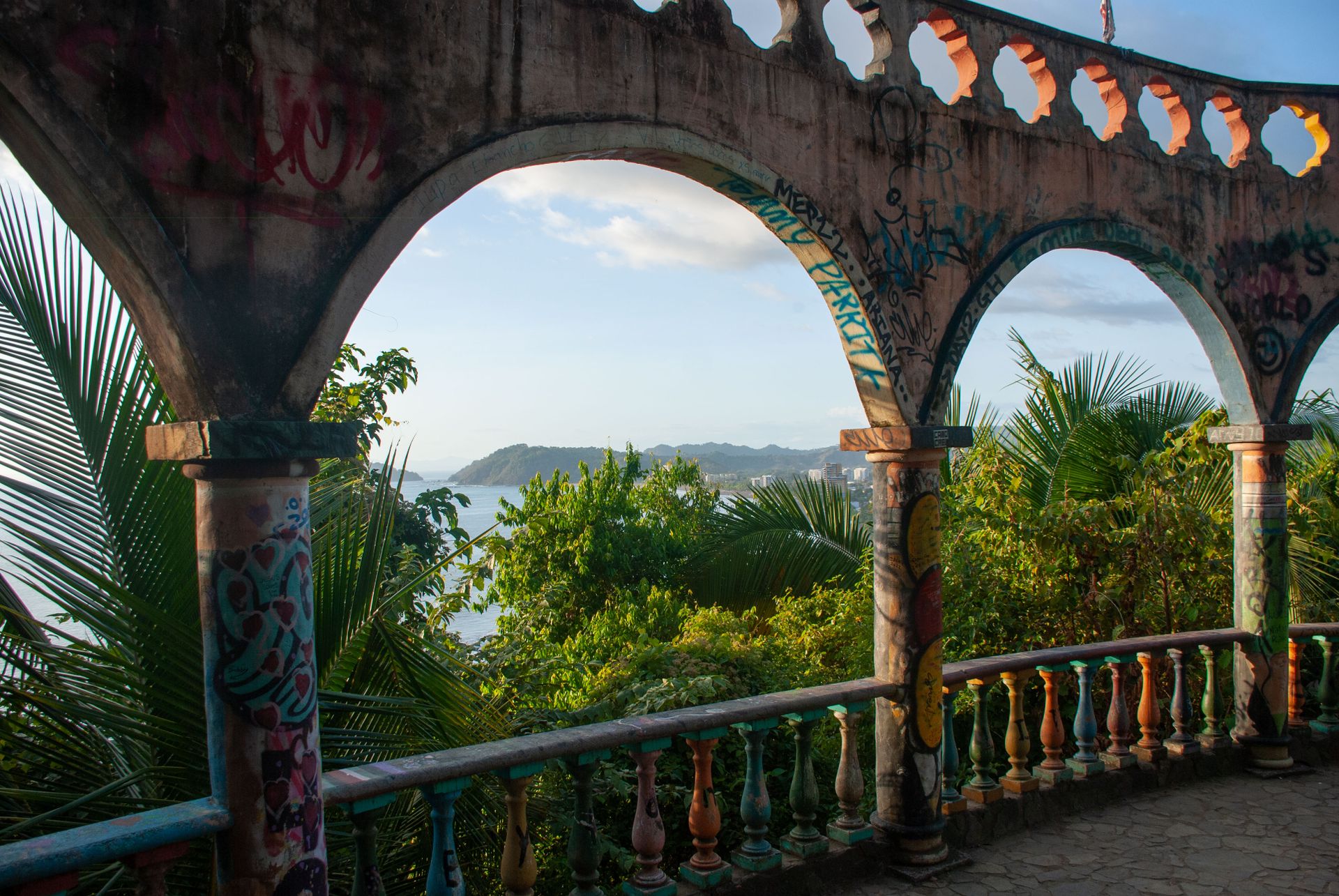 Vibrant tropical landscape of Jaco, Costa Rica viewed through graffiti-covered arches. Perfect for travel and nature lovers.