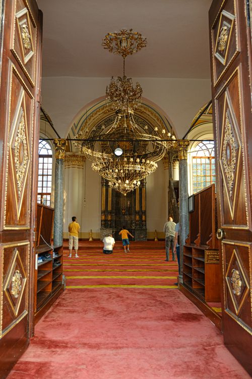 Free Elegant mosque interior with ornate doors and worshippers in prayer. Stock Photo