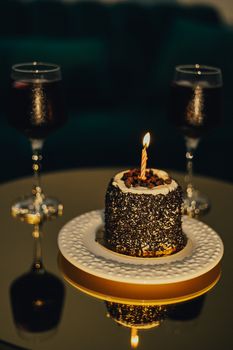 A beautiful dessert with a lit candle and two wine glasses, perfect for celebrations.